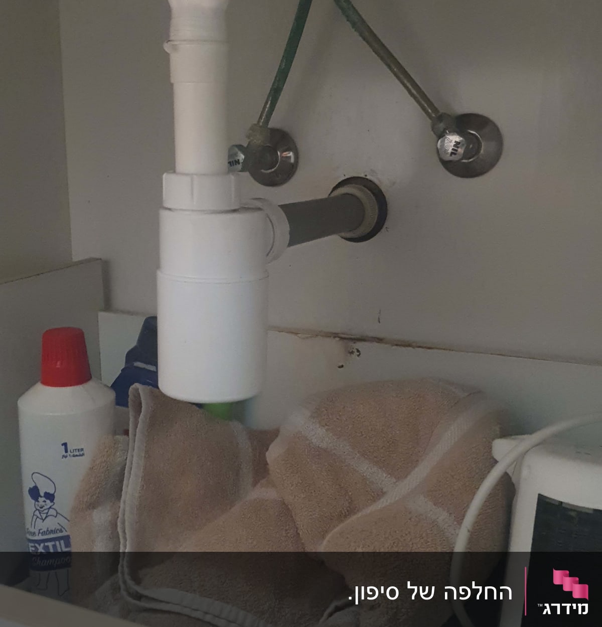 צנרת מתחת לכיור עם מגבת וחומר ניקוי